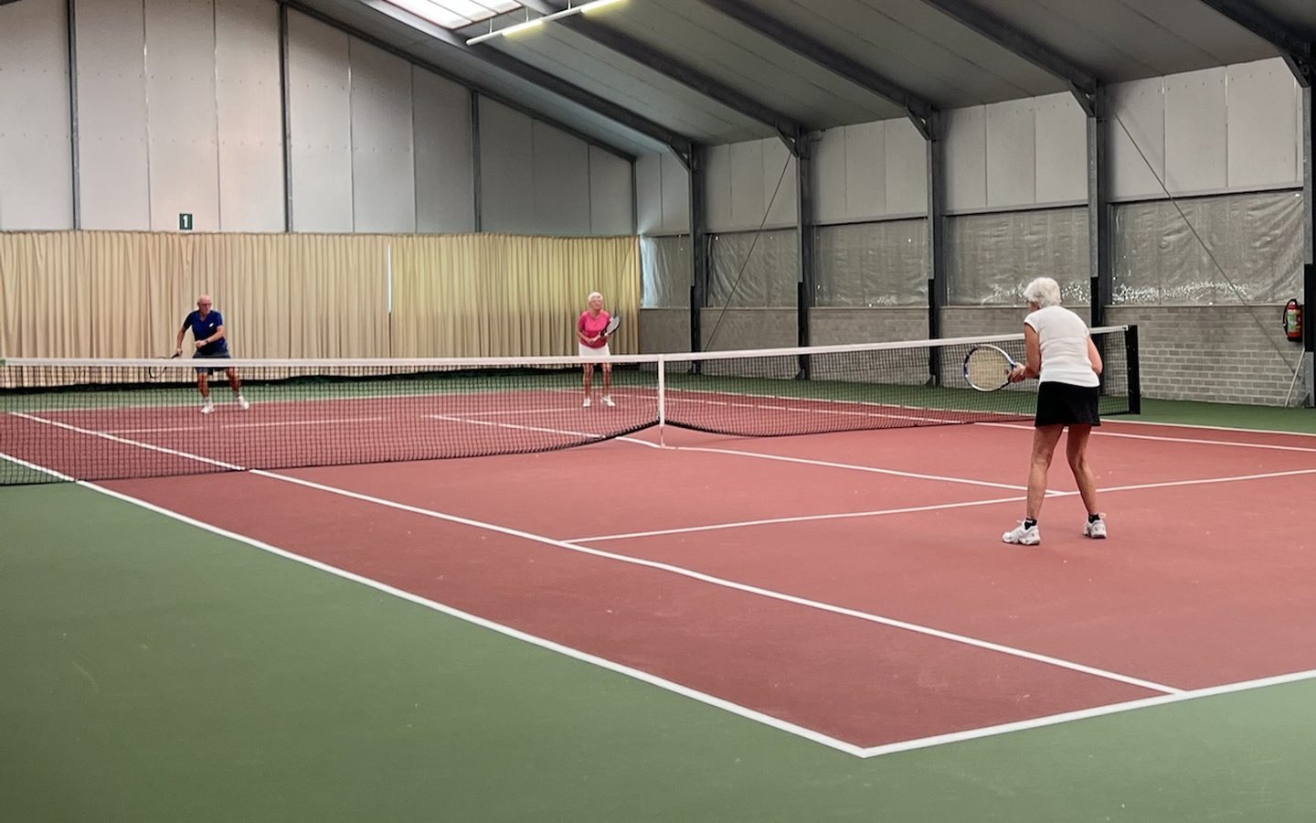 Vier spelers spelen een dubbel op baan 1 van Tennishal Zwaanshoek